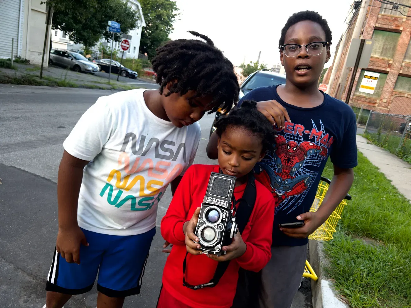Three children on a Bridgeport street, the youngest holding the Rolleiflex and looking down into its waist-level finder.