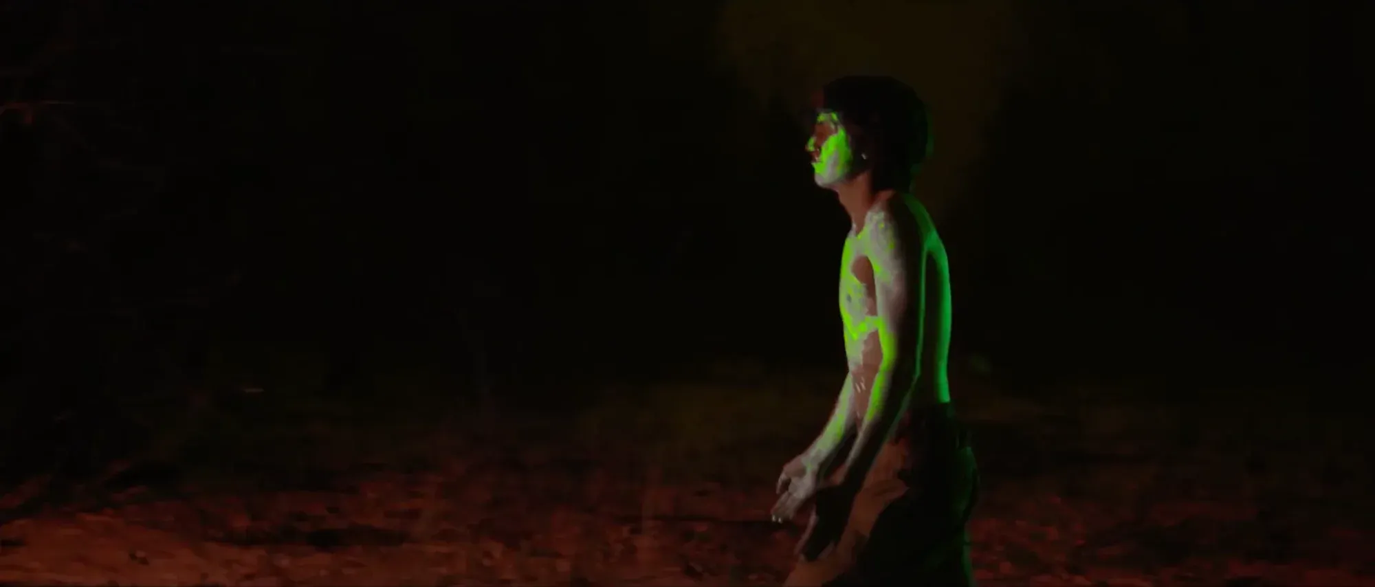 Film still from Bioluminescence — fluorescent paint glowing under UV light.