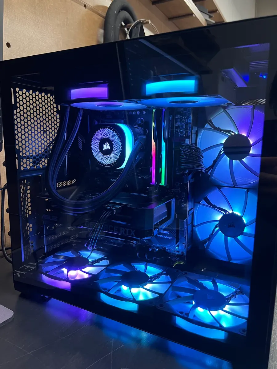 A glass-sided PC tower lit blue and violet, with a Corsair liquid cooler, G.Skill memory and a GeForce RTX graphics card.